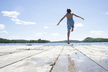 Pre Teen Boy Jumping Off Dock at Cottage