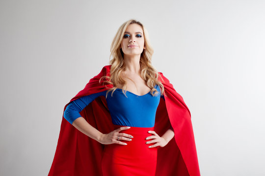 Superhero Woman. Young and beautiful blonde in image of superheroine in red Cape growing