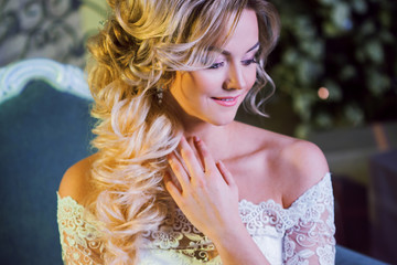 Portrait of charming woman in wedding dress. The girl bride sits in a chair