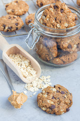 Flourless gluten free peanut butter, oatmeal and chocolate chips cookies in glass jar and on table, vertical