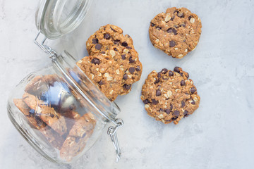 Flourless gluten free peanut butter, oatmeal and chocolate chips cookies in glass jar, top view, horizontal