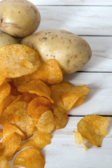 Fresh raw potatoes and chips with spice on a white wooden background