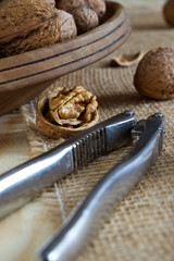 walnuts and a nutcracker on a wooden table, a bowl full of nuts 