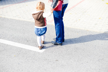 Back view of parent with child walking on sunny road outdoors background. Childcare, love and safety lifestyle