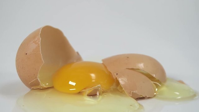 Egg breaking after being dropped to reveal broken shell and egg yolk 