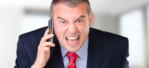 Angry businessman screaming into the mobile phone