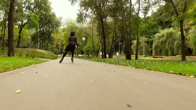 Inline skates. Dark-haired stylish woman moving on roller skates. The view from the back. 4K