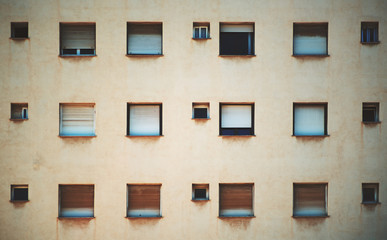 Fototapeta premium Beige facade of residential building in Barcelona with regular pattern of windows of different size, streaks of rust under the sills