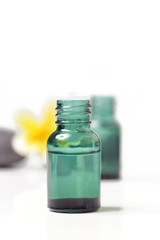 Green cosmetic bottles with zen stones and frangipani flower