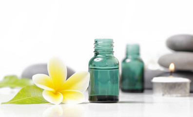 Obraz na płótnie Canvas Green cosmetic bottles with zen stones and frangipani flower