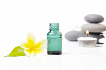 Obraz na płótnie Canvas Green cosmetic bottles with zen stones and frangipani flower