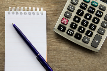 Top view of note book with pen and calculator on wooden table ba