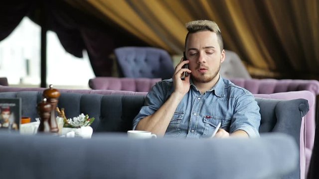 Lonely young man talking on the phone in restaurant
