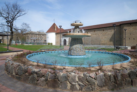 The city fountain at walls of the Herman castle in the sunny spring afternoon. Narva, Estonia
