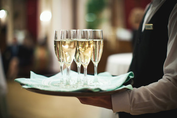 Waiter serving champagne on a tray at the hotel restaurant - Powered by Adobe