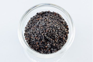 Pile of black sesame seeds on bow  isolated on white background