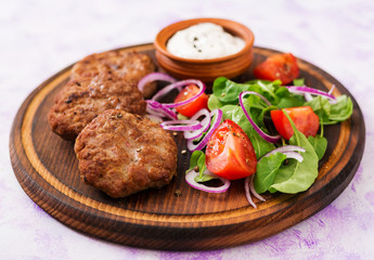 Appetizing meat cutlet and tomato salad with arugula