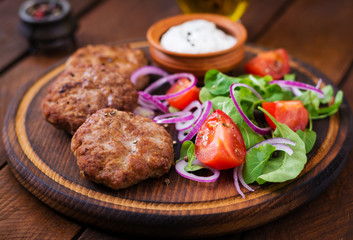 Appetizing meat cutlet and tomato salad with arugula