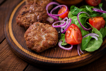 Appetizing meat cutlet and tomato salad with arugula