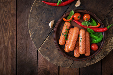Grilled sausages and vegetables on a wooden background in rustic style. Flat lay. Top view