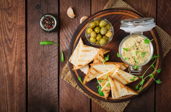 Pate Chicken - rillette, toast, olives and herbs on a wooden board. Flat lay. Top view