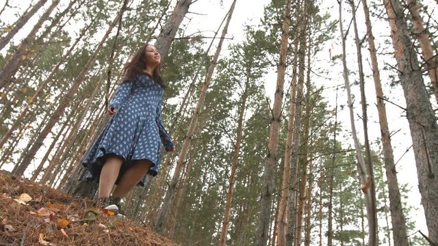 Dancing in the pine forest. 2 Shots.

Young pretty girl in a blue dress standing leaning on a pine tree.