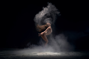 Fototapeta na wymiar Dancer in motion in cloud of powder, studio shot 