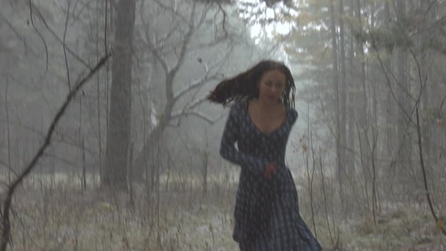 Forest chase. Slow motion.

Snowfall in the gloomy winter forest. Beautiful girl is afraid and runs away.