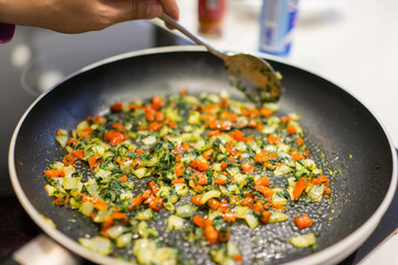 Frying pan on stove with pepper and mushrooms, closeup