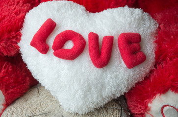Red love  text  on teddy bear for Valentines Day with white heart  on wooden floor