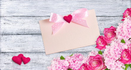 Fototapeta na wymiar Pink roses and hydrangeas with hearts and card 
