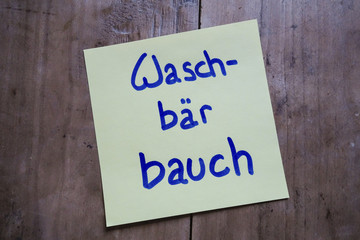 Post it memo on wooden table, Waschbärbauch