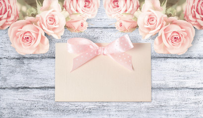 Roses with paper card on background of shabby wooden planks.