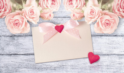 Roses with card and hearts on background of shabby wooden planks.
