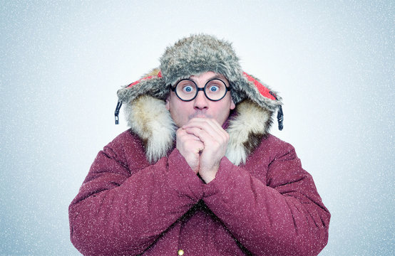 Frozen man in winter clothes and glasses warming hands, cold, snow, blizzard