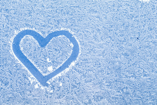 Sign of love heart painted on frosted winter window glass with f
