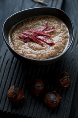 Close-up of chestnut cream-soup with smoked meat topping