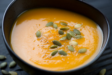 Close-up of pumpkin cream-soup in a black ceramic bowl