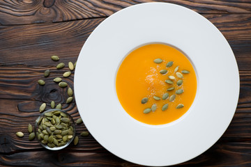 White glass plate with pumpkin cream-soup, flat-lay view