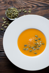 Pumpkin cream-soup with pumpkin seeds served in a white plate