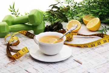 ginger tea - fitness liefestyle concept with tea, dumbells and measure tape