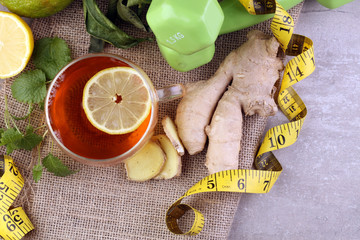 ginger tea - fitness liefestyle concept with tea, dumbells and measure tape - Healthy  tea detox