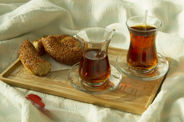 Morning turkish tea in traditional glass with bagel on the tray