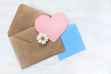  romantic Valentine card/ open envelope with a heart symbol and chamomile lying on a light table top view 
