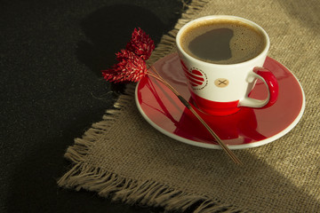 Red cup of coffee with flower on linen cloth