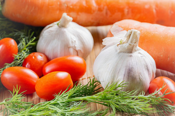 Vegetables on bamboo table cloth. Fresh cherry tomatoes, garlic, carrot, dill close up