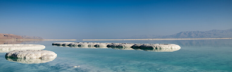 Naklejka na ściany i meble Panoramic view of dead sea salt on beach at sunrise. Israel