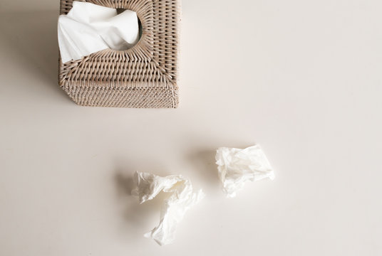 High angle view of white rattan tissue box and crumpled tissues on table - cold and flu season concept, grief concept