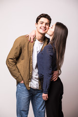 Portrait of beautiful smiling couple kissing at studio over white background.