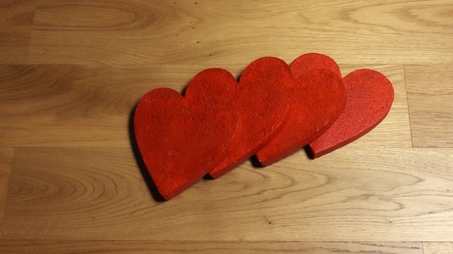Woman hand pushes red heart shape with domino effect